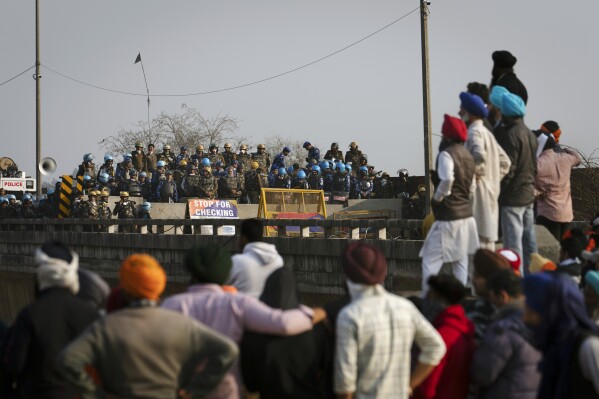 Protesting farmers stand facing the police barricade near Shambhu border that divides northern Punjab and Haryana states, almost 200 kilometers (125 miles) from New Delhi, India, Friday, Feb.16, 2024. Farmers are blocking highways and holding demonstrations in many rural areas in northern India to protest over a range of grievances that have also led tens and thousands to march toward the capital. (AP Photo/Altaf Qadri)