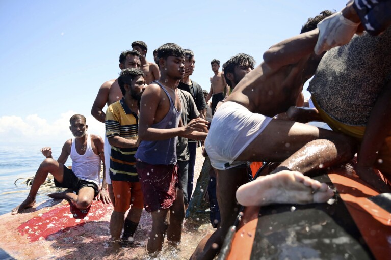 Rohingya refugees climb onto a National Search and Rescue Agency boat as they are being rescued after their boat capsized in the waters off West Aceh, Indonesia, Thursday, March 21, 2024. The wooden boat carrying dozens of Rohingya Muslims capsized off Indonesia's northernmost coast on Wednesday, according to local fishermen. (AP Photo/Reza Saifullah)