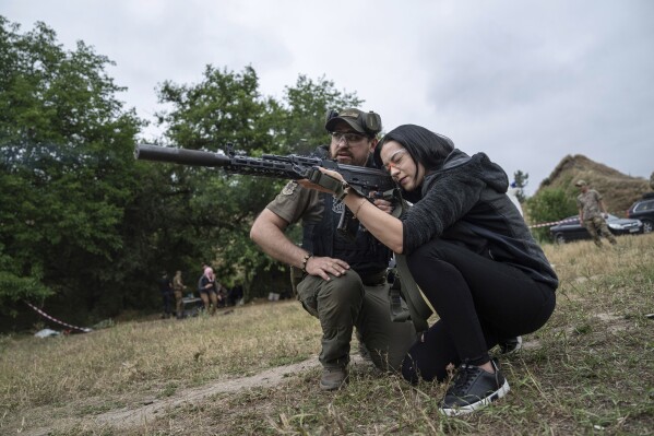 A woman fires an AK-47 during a tactical training for civilians near Zaporizhzhia, Ukraine, Sunday, July 9, 2023. (AP Photo/Evgeniy Maloletka)