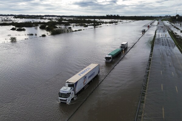 Semi-trucks drive through a flooded highway after heavy rains in Campana, Argentina, Saturday, May 17, 2025. (AP Photo/Rodrigo Abd)