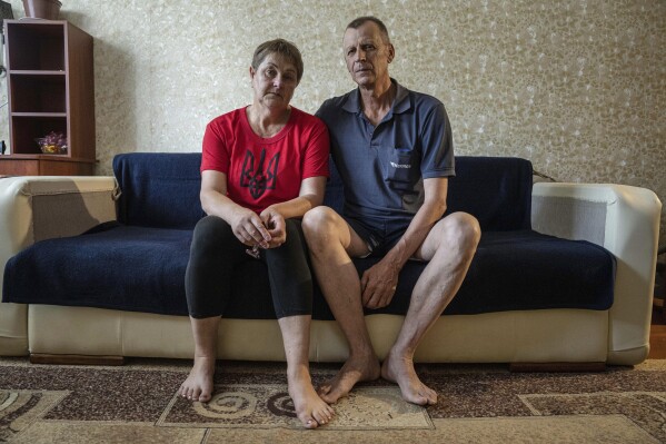 Nataliia Skakun and her husband Serhii, former residents of Oleshky, Ukraine, sit on a sofa at their apartments in Mykolaiv, Ukraine, Tuesday, July 4, 2023. "Young people left, and pensioners stayed," said Skakun, 54, who recently left Oleshky with her husband and resettled in Mykolaiv in the Kherson region. (AP Photo/Evgeniy Maloletka)