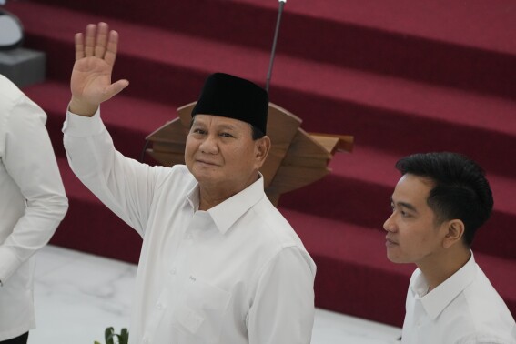 Indonesian Defense Minister and president-elect Prabowo Subianto, left, waves at media members as his running mate Gibran Rakabuming Raka, the eldest son of Indonesian President JokoWidodo, looks on during their formal declaration as president and vice president-elect at the General Election Commission building in Jakarta, Indonesia, Wednesday, April 24, 2024. Indonesia's electoral commission formally Subianto as the elected president in a ceremony on Wednesday after the country's highest court rejected appeals lodged by two losing presidential candidates who are challenging his landslide victory. (AP Photo/Dita Alangkara)