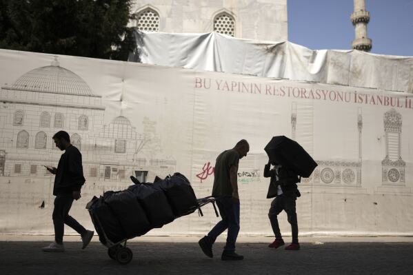 People carry goods in the Eminonu commercial district of Istanbul, Turkey, Thursday, April 17, 2025. (AP Photo/Francisco Seco)