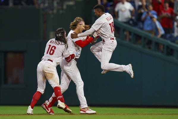 Philadelphia Phillies' Alec Bohm, center, celebrates with Brandon Marsh, left, and Johan Rojas, right, after driving in the game winning run with a single in the ninth inning of baseball game against the Baltimore Orioles, Tuesday, July 25, 2023, in Philadelphia. The Phillies won 4-3. (AP Photo/Chris Szagola)