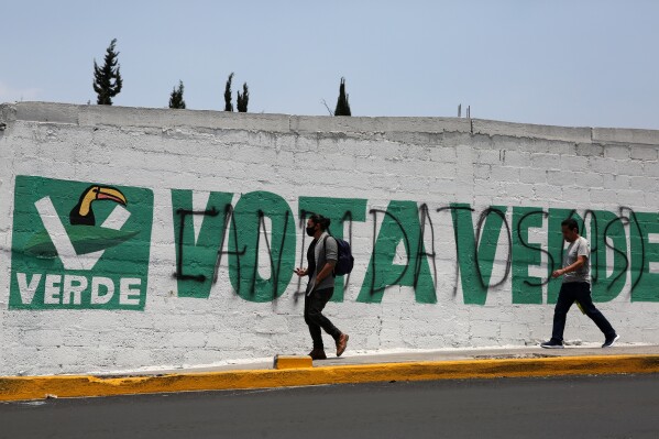 FILE - Pedestrians walk by an campaign mural emblazoned with a 