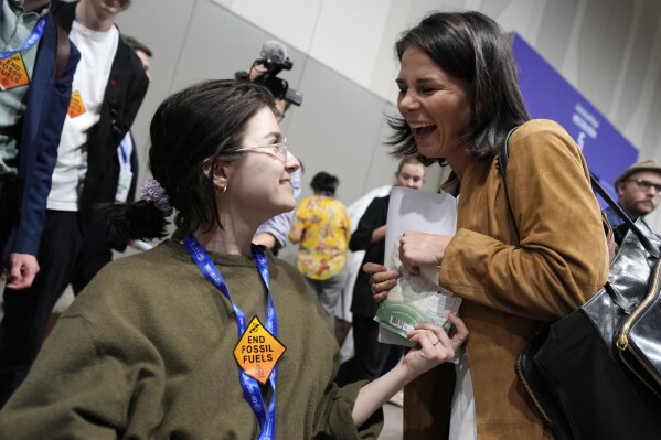 Germany Foreign Minister Annalena Baerbock, right, accepts an item from an activist as she heads to a new session of talks at the COP28 U.N. Climate Summit, Monday, Dec. 11, 2023, in Dubai, United Arab Emirates. (AP Photo/Peter Dejong)