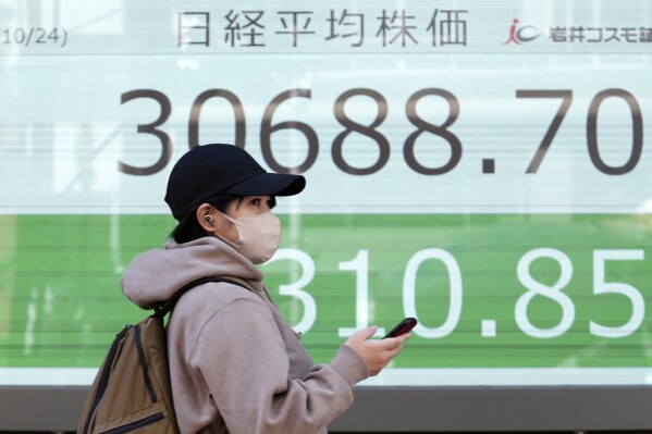 A person walks in front of an electronic stock board showing Japan's Nikkei 225 index at a securities firm Tuesday, Oct. 24, 2023, in Tokyo. Shares were mixed Tuesday in Asia after Wall Street wobbled to a mixed close as yields on U.S. Treasury bonds fell back after creeping above 5%. (AP Photo/Eugene Hoshiko)