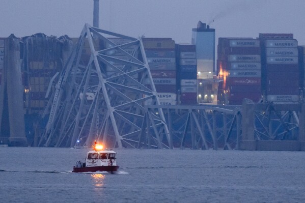 A container ship rests against wreckage of the Francis Scott Key Bridge near sunrise on Wednesday, March 27, 2024, in Baltimore, Md. (AP Photo/Matt Rourke)