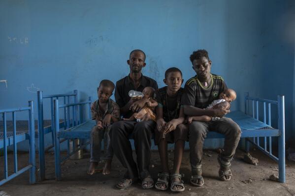Tigrayan refugee Abraha Kinfe Gebremariam, 40, second left, sits for a photograph with his sons, Micheale, 5, left; Daniel, 11, center; his 19-year-old brother-in-law, Goytom Tsegay, second right, and his 4-month-old twin daughters Aden, right, and Turfu Gebremariam, on his lap, inside their family's shelter in Hamdayet, eastern Sudan, near the border with Ethiopia, on March 23, 2021. A fellow refugee, Mulu Gebrencheal, a mother of five, has become an informal adviser, offering guidance on the babies’ care. Abraha and his sons are quick learners, she said. But she mourns for the twins and the death of their mother. “Even the hug of a mother is very sweet,” she said. “They’ve never had this. They never will.” (AP Photo/Nariman El-Mofty)