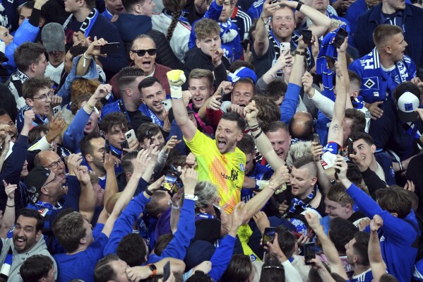 Hamburg goalkeeper Daniel Heuer Fernandes celebrates with fans who stormed the pitch to celebrate promotion following a Bundesliga 2 soccer game between Hamburger SV and SSV Ulm 1846 in Hamburg, Germany, Saturday, May 10, 2025. (Marcus Brandt/dpa via AP)