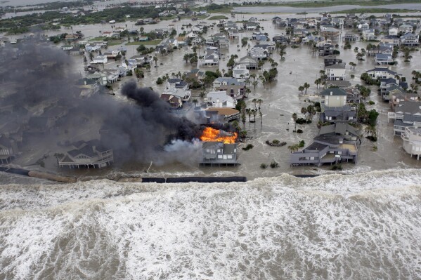 FILE - Fire destroys homes along the beach on Galveston Island, Texas, as Hurricane Ike approaches, Sept. 12, 2008. Hurricanes beginning with the letter "I" have been among the most destructive to strike the United States, moreso than any other letter of the alphabet. Idalia is on a path to strike Florida's Gulf Coast as a major hurricane to join the long list of catastrophic examples. (AP Photo/David J. Phillip, File)