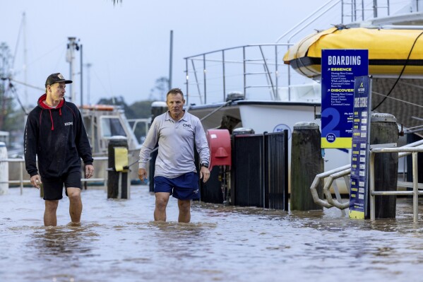 Conor Lang and Anthony Heeney walk through flooded areas in Port Macquarie, north of Sydney, Australia, Wednesday, May 21, 2025. (Lindsay Moller/AAP Image via AP)
