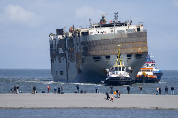 Stricken cargo ship Fremantle Highway, that caught fire while transporting thousands of cars, including nearly 500 electric vehicles, from Germany to Singapore, is towed into the port of Eemshaven, the Netherlands, on Thursday, Aug. 3, 2023. The ship that burned for almost a week close to busy North Sea shipping lanes and a world renowned migratory bird habitat will be salvaged at the northern Dutch port. (AP Photo/Peter Dejong)