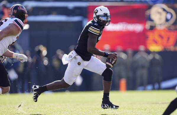 Colorado quarterback Shedeur Sanders avoids Oklahoma State safety Talon Kendrick in the first half of an NCAA college football game Friday, Nov. 29, 2024, in Boulder, Colo. (AP Photo/David Zalubowski)
