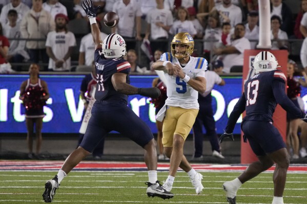 UCLA quarterback Collin Schlee (9) throws a pass over Arizona linebacker Taylor Upshaw (11) during the first half of an NCAA college football game Saturday, Nov. 4, 2023, in Tucson, Ariz. (AP Photo/Rick Scuteri)