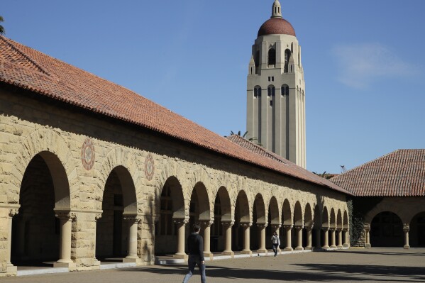 FILE - People walk on the Stanford University campus beneath Hoover Tower, March 14, 2019, in Stanford, Calif. Following a lawsuit filed Monday, Sept. 18, 2023, that alleges Stanford University received millions of dollars in donations from FTX Trading, the school said Wednesday, Sept. 20, that it will return the funds of all gifts collected from the now-collapsed cryptocurrency exchange. (AP Photo/Ben Margot, File)