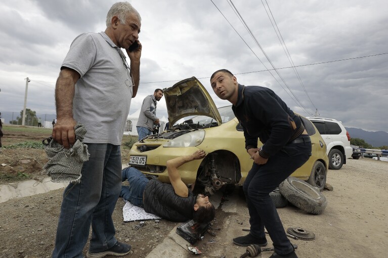 Ethnic Armenians from Nagorno-Karabakh repair their car on the road from Nagorno-Karabakh to Kornidzor, in Armenia's Syunik region, Tuesday, Sept. 26, 2023. (AP Photo/Vasily Krestyaninov)