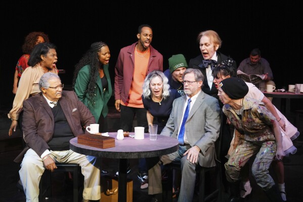 This image shows Count Sovall, seated left, and John L. Payne, seated right, with the cast during a performance of "American Rot," playing through March 31 at the Ellen Stewart Theatre in New York. (Steven Pisano/Sam Rudy Public Relations via AP)