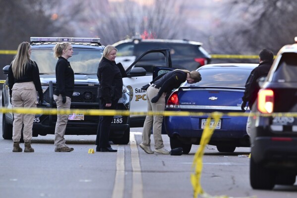 Investigators examine a car with a broken door window at the scene where a St. Paul police officer was wounded in the leg in an exchange of gunfire with a suspect at the intersection of Cretin and Marshall Ave. in St. Paul, Minn. on Thursday, Dec. 7, 2023. (John Autey/Pioneer Press via AP)
