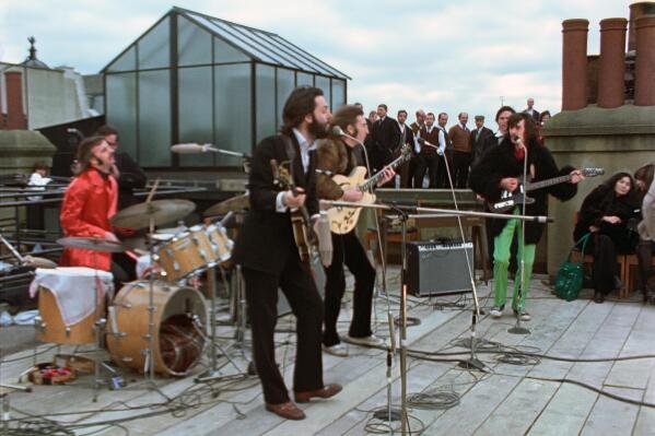 This image released by Disney+ shows, from left, Ringo Starr, Paul McCartney, John Lennon and George Harrison, with Yoko Ono, seated right, in a scene from the nearly 8-hour Peter Jackson-produced documentary “Get Back,” airing over three days starting Thanksgiving. (Disney+ via AP)