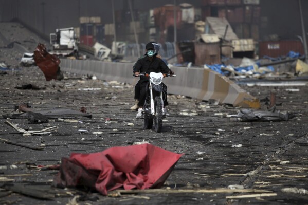 In this photo provided by Islamic Republic News Agency, IRNA, two men on a motorcycle drive through debris after a massive explosion rocked a port near the southern port city of Bandar Abbas, Iran, Saturday, April 26, 2025. (Mohammad Rasoul Moradi/IRNA via AP)