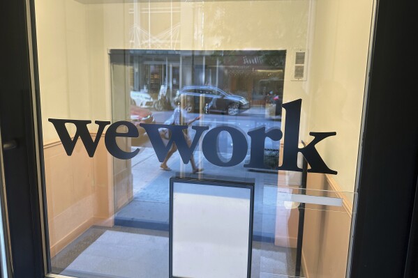 FILE - A sign for WeWork is displayed at the workspace-sharing office in the borough of Manhattan in New York, Aug. 9, 2023. WeWork said on Tuesday, Aug. 8, that there was “substantial doubt” on its ability to stay in business, prompting speculation around the future of the troubled workspace-sharing company. (AP Photo/Ted Shaffrey, File)