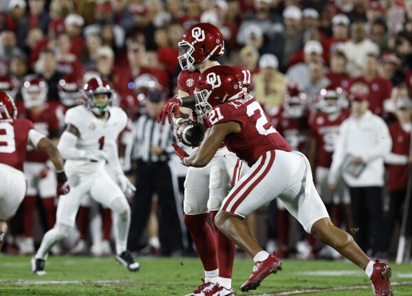 Oklahoma quarterback Jackson Arnold (11) hands off the ball to Oklahoma running back Xavier Robinson (21) during the first quarter of a NCAA college football game against Alabama on Saturday, Nov. 23, 2024, in Norman, Okla. (AP Photo/Alonzo Adams)