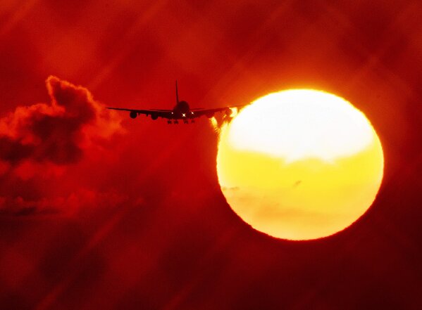 FILE - In this Wednesday, Aug. 21, 2019 file photo, an aircraft passes the rising sun as it approaches the airport in Frankfurt, Germany. The European Union says it will miss its targets for reducing planet-warming greenhouse gases by 2030 unless member states make a greater effort than they have so far. (AP Photo/Michael Probst, File)