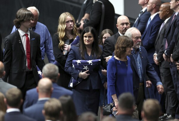 Kelly Weeks, center, the widow of slain Deputy U.S. Marshal Thomas Weeks Jr., glances over at attendees of her husband's memorial service at Bojangles Coliseum in Charlotte, N.C., on Monday, May 6, 2024. (Jeff Siner/The Charlotte Observer via AP)