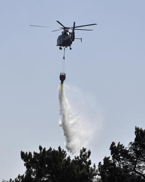 A helicopter drops water in a wildfire at a national park at the Dutch-German border near Herkenbosch, Netherlands, Wednesday, April 22, 2020. Due to the long dryness the danger of forest fires increases all over Germany. (AP Photo/Martin Meissner)