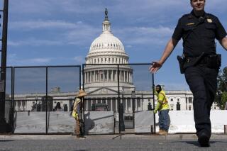 U.S. Capitol police officer push back people who are watching workers remove the fence surrounding the U.S. Capitol building, after six months was erected, following the Jan. 6 riot at the Capitol, on Saturday, July 10, 2021, in Washington. (AP Photo/Jose Luis Magana)