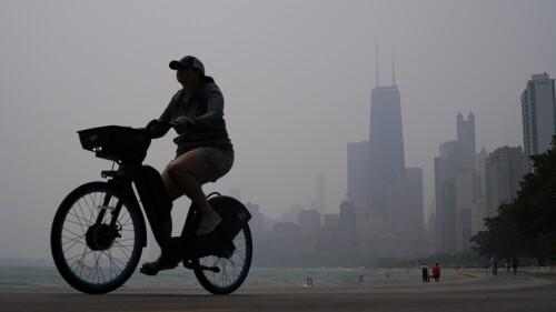 Una persona monta una bicicleta junto a la orilla del lago Michigan, el martes 27 de junio de 2023, en Chicago. (AP Foto/Kiichiro Sato)