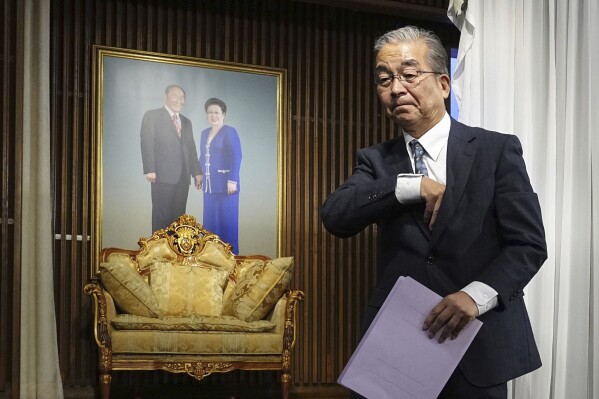 Nobuo Okamura, the legal affairs department chief for the Unification Church, walks past a portrait of its founder Sun Myung Moon, left, and his wife Hak Ja Han, as he leaves a news conference at the church's Japan headquarters in Tokyo, Monday, Oct. 16, 2023. The Japanese branch of the Unification Church on Monday criticized the Japanese government's request for a court order to dissolve the group, saying it's based on groundless accusations and is a serious threat to religious freedom and human rights of its followers. (Ichiro Sakano/Kyodo News via AP)