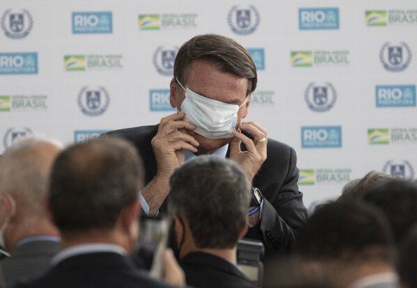 Brazil's President Jair Bolsonaro puts on a mask due to the COVID-19 pandemic during the inauguration of the new General Abreu civic-military school in Rio de Janeiro, Brazil, Friday, Aug. 14, 2020. (AP Photo/Silvia Izquierdo)
