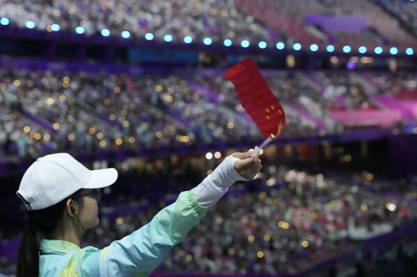 A volunteer waves a flag ahead of the opening ceremony of the 19th Asian Games in Hangzhou, China, Saturday, Sept. 23, 2023. (AP Photo/Eugene Hoshiko)