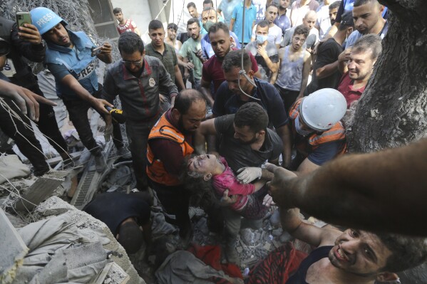 FILE - Palestinians rescue a child from under the rubble after Israeli airstrikes in Gaza City, Gaza Strip, Wednesday, Oct. 18, 2023. Israel's war on Hamas in the Gaza Strip has the Mideast simmering, raising the temperature on tensions across the region and increasing the risk that seemingly localized conflicts could spin out of control. (AP Photo/Abed Khaled, File)