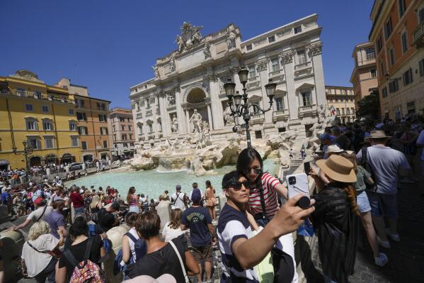 Tourists take a selfie in front of the Trevi Fountain, in Rome, Monday, June 20, 2022. Summer travel is underway across the globe, but a full recovery from two years of coronavirus could last as long as the pandemic itself. In Italy, tourists — especially from the U.S. — returned this year in droves. (AP Photo/Andrew Medichini)