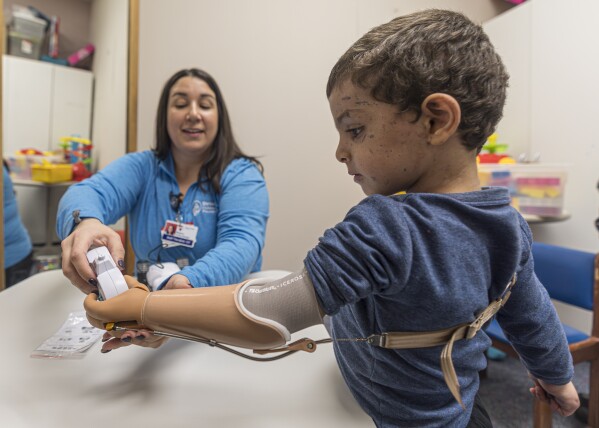 Four-year-old Omar Abu Kuwaik learns to use his new prosthetic arm with occupational therapist Meghan Gossenberger at Shriners Children's Hospital, Wednesday, Feb. 28, 2024, in Philadelphia. (AP Photo/Peter K. Afriyie)