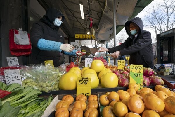A shopper, right, buys produce from a vendor during the coronavirus pandemic, Tuesday, Jan. 19, 2021, in New York. The city will run out of first doses of COVID-19 vaccine sometime Thursday without fresh supplies, Mayor Bill de Blasio said Tuesday.(AP Photo/Mark Lennihan)