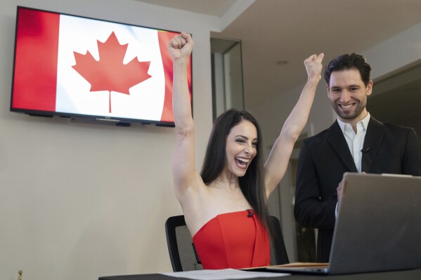Figure Skater Deanna Stellato-Dudek bereaksi setelah menjadi warga negara Kanada, seperti yang dipandang mitra Maxime Deschamps di Montreal pada hari Rabu, 11 Desember 2024. (Christinne Muschi /The Canadian Press via AP)