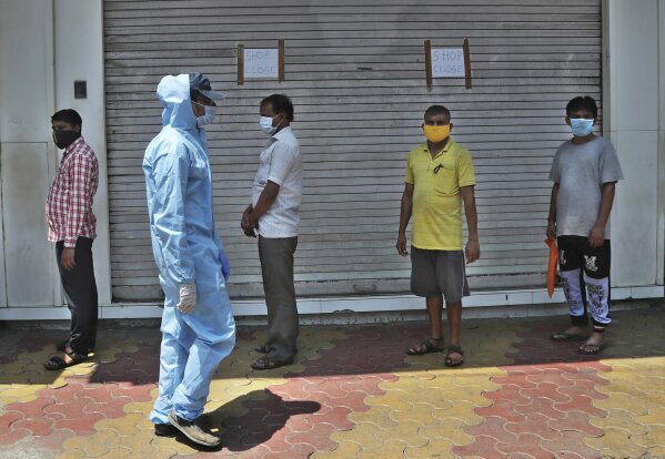 People wearing masks stand in a queue to receive food being distributed during lockdown in Mumbai, India, Sunday, March 29, 2020. Indian Prime Minister Narendra Modi apologized to the public on Sunday for imposing a three-week national lockdown, calling it harsh but "needed to win" the battle against the coronavirus pandemic. The new coronavirus causes mild or moderate symptoms for most people, but for some, especially older adults and people with existing health problems, it can cause more severe illness or death. (AP Photo/Rafiq Maqbool)