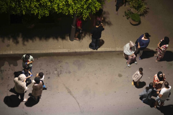 People take shelter and check for news on their mobile phones after an earthquake in Rabat, Morocco, Friday, Sept. 8, 2023. A powerful earthquake struck Morocco late Friday, damaging buildings in major cities and sending panicked people pouring into streets and alleyways from Rabat to Marrakech. (AP Photo/Mosa'ab Elshamy)