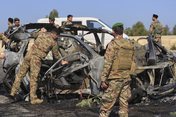 Lebanese army soldiers inspect a charred car that was hit by an Israeli strike, in the southern coastal town of Ghazieh, Lebanon, Friday, April 18, 2025. (AP Photo/Mohammed Zaatari)