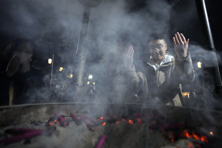 People pray at Zojoji Buddhist temple on New Year's Eve Sunday, Dec. 31, 2023, in Tokyo. (AP Photo/Eugene Hoshiko)