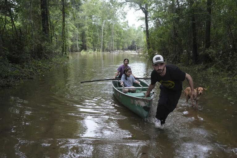 Alvaro Trevino pulls a canoe with Jennifer Tellez and Ailyn, 8, after they checked on their home on Sunday, May 5, 2024, in Spendora, Texas. The family has lived on the property in a rental trailer for two years. 