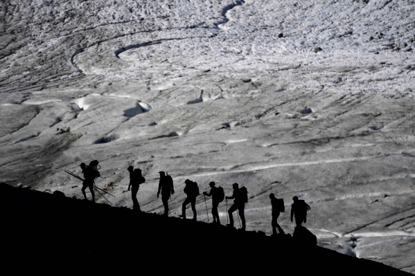 A group walks to the Jamtalferner Glacier near Galtuer, Austria, Wednesday, Sept. 6, 2023.(AP Photo/Matthias Schrader)