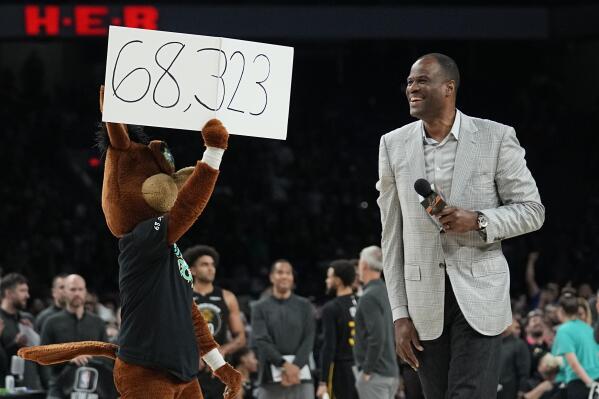 Former San Antonio Spurs player David Robinson, right, with help from the Spurs' mascot, announces the attendance at an NBA basketball game between the Spurs and the Golden State Warriors in San Antonio, Friday, Jan. 13, 2023. The announced attendance of 68,323 sets a new NBA regular-season game attendance record. (AP Photo/Eric Gay) an NBA regular-season