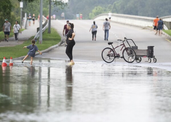 People gather to walk around the Lake Houston Bridge along the West Lake Houston Parkway after it was closed due to high water on either side of the thoroughfare, Saturday, May 4, 2024, in Kingwood, Texas (Jason Fochtman/Houston Chronicle via AP)