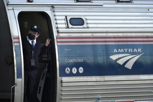 FILE - A conductor makes sure all is clear as the Amtrak Downeaster passenger train pulls out of the station, Dec. 14, 2021, in Freeport, Maine. Riders on the Amtrak train that runs from Maine to Boston will soon have to hold off on buying alcoholic beverages during the 35-mile stretch of the trip that goes through New Hampshire. (AP Photo/Robert F. Bukaty, File)