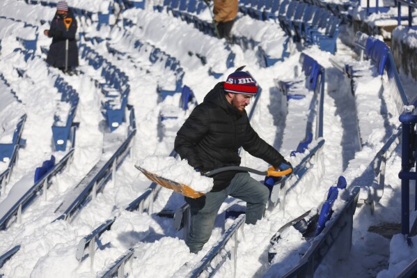 A stadium worker clears snow from seats before an NFL wild-card playoff football game between the Buffalo Bills and the Pittsburgh Steelers, Monday, Jan. 15, 2024, in Buffalo, N.Y. (AP Photo/Jeffrey T. Barnes)